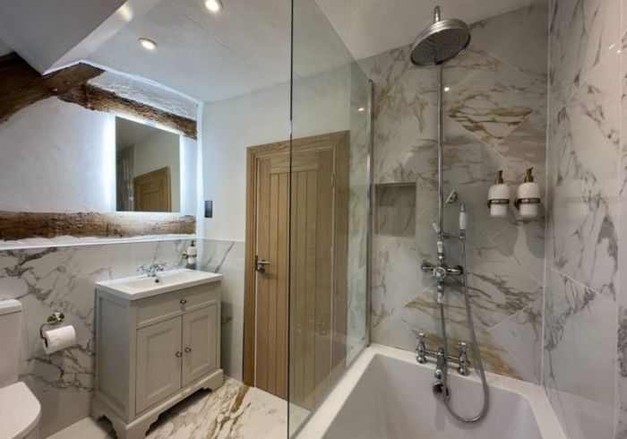 A bathroom with a bathtub , sink , mirror and shower.