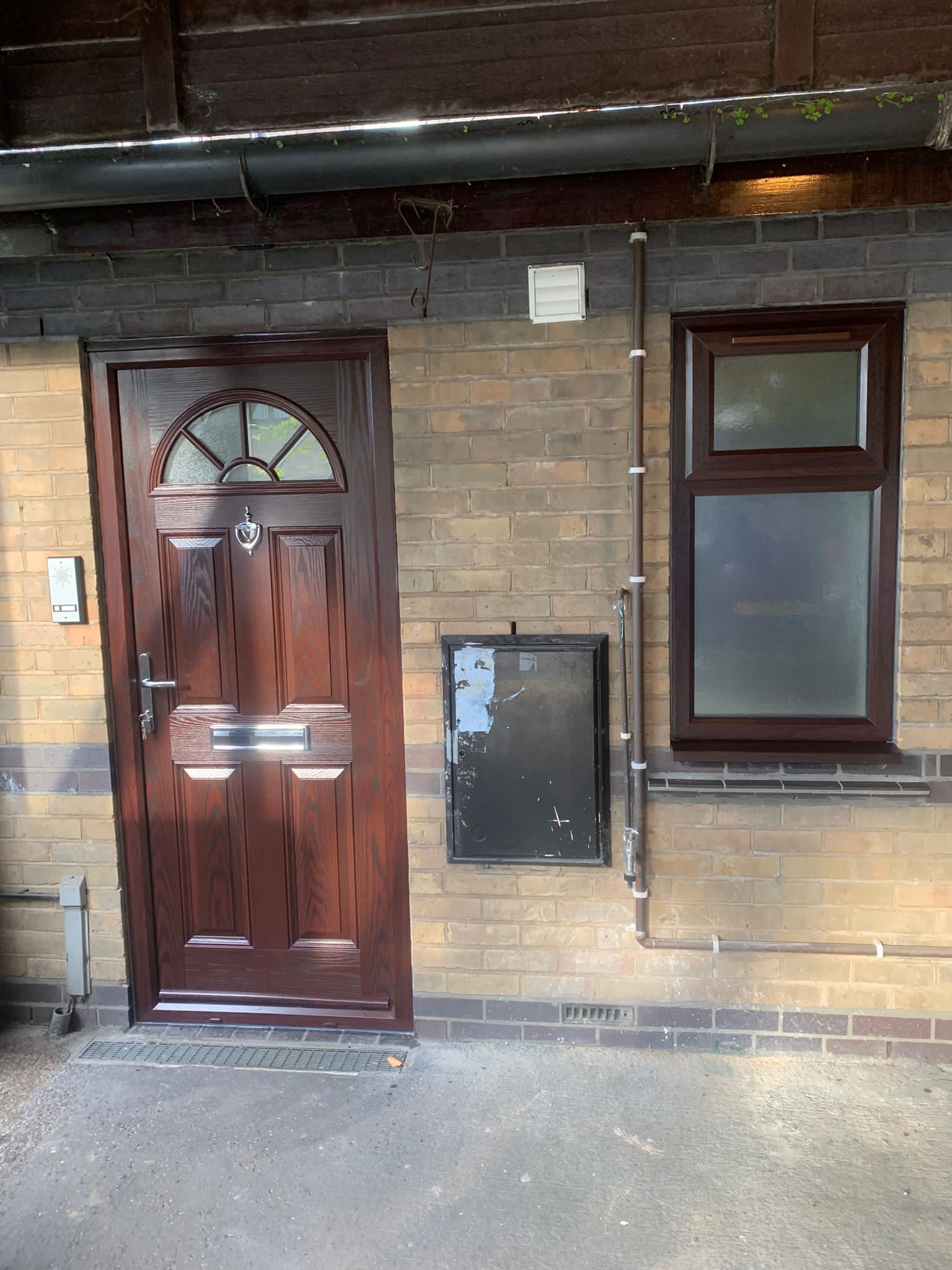 A brown door is sitting on a brick wall next to a window.