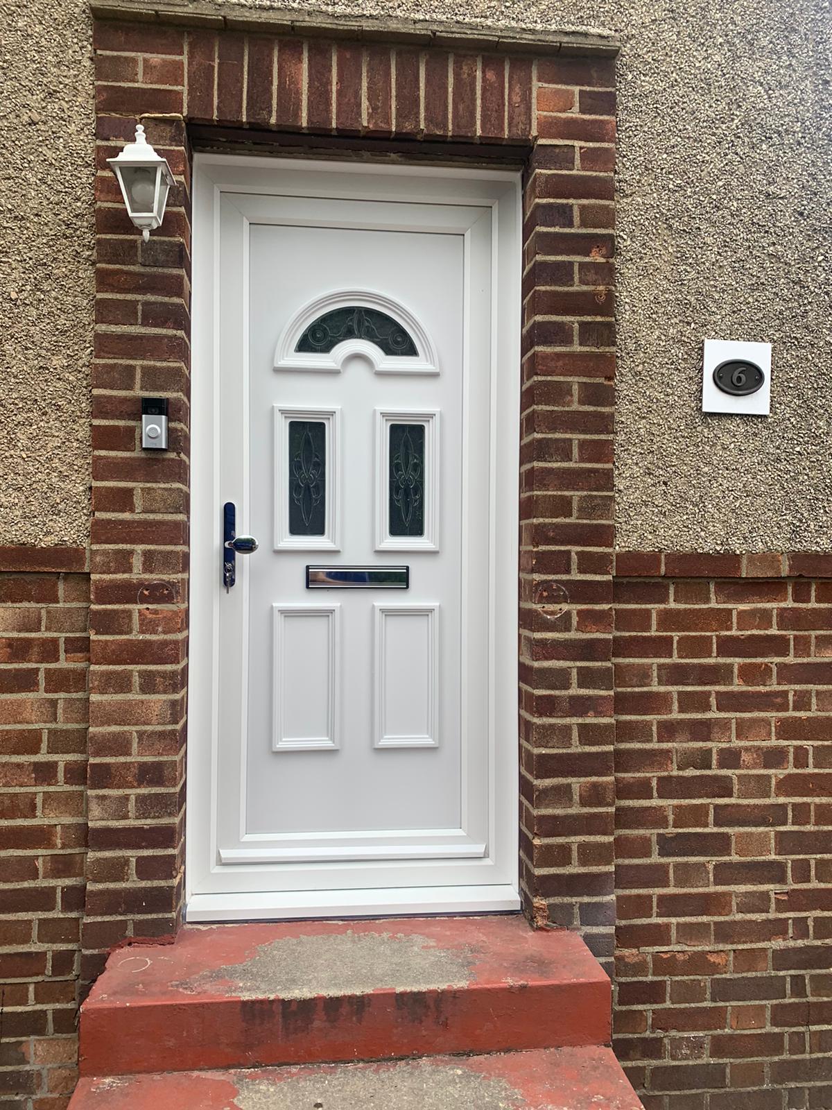 A white door is sitting on top of a brick wall.