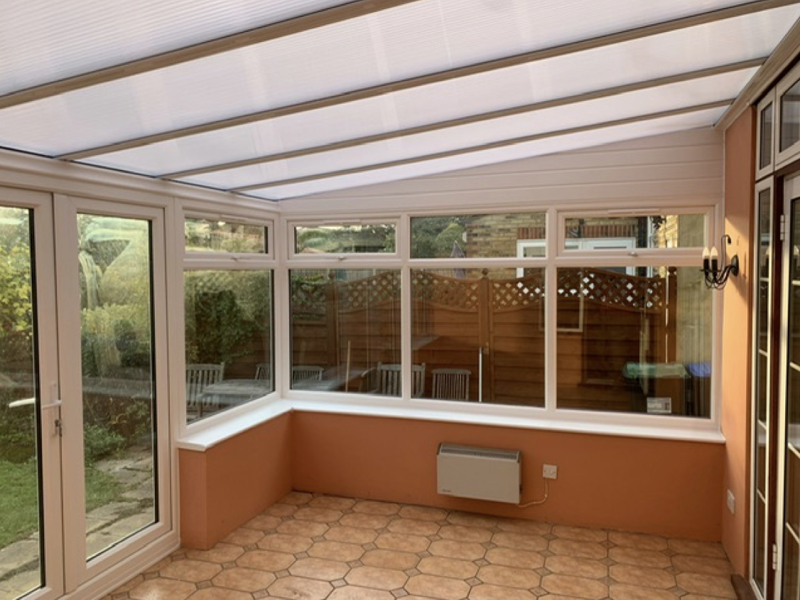 an empty conservatory with a white roof and a lot of windows .