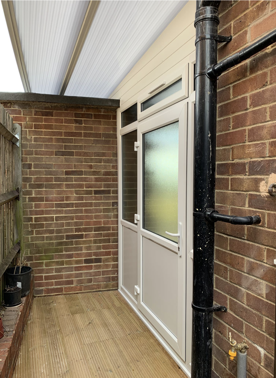 A brick building with a white door and a black pipe.