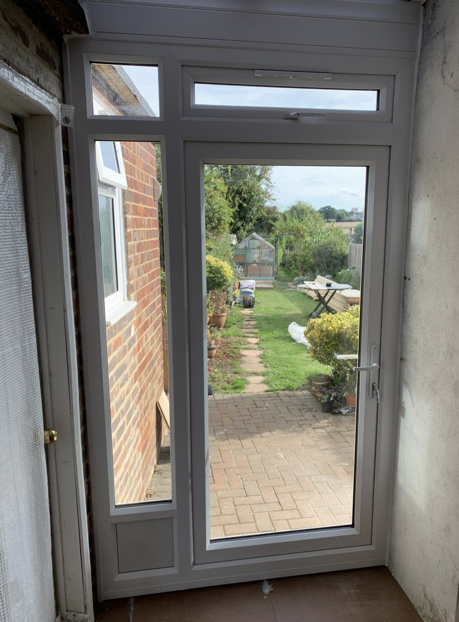 A door with a view of a garden and a brick wall.