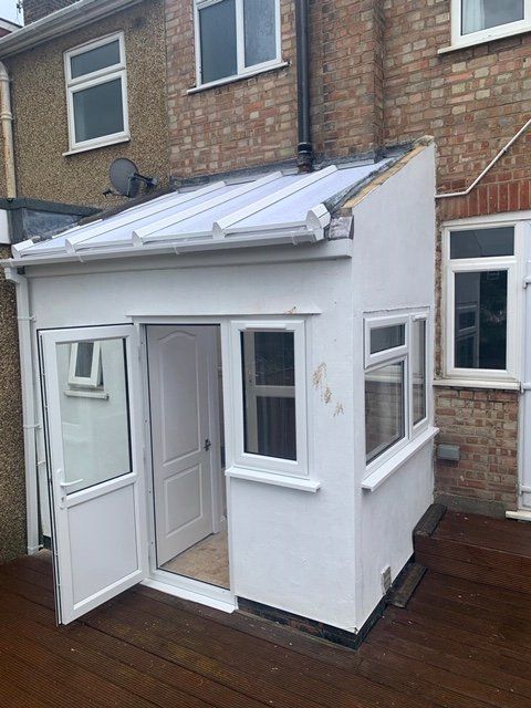 A white extension to a brick house with a glass roof.