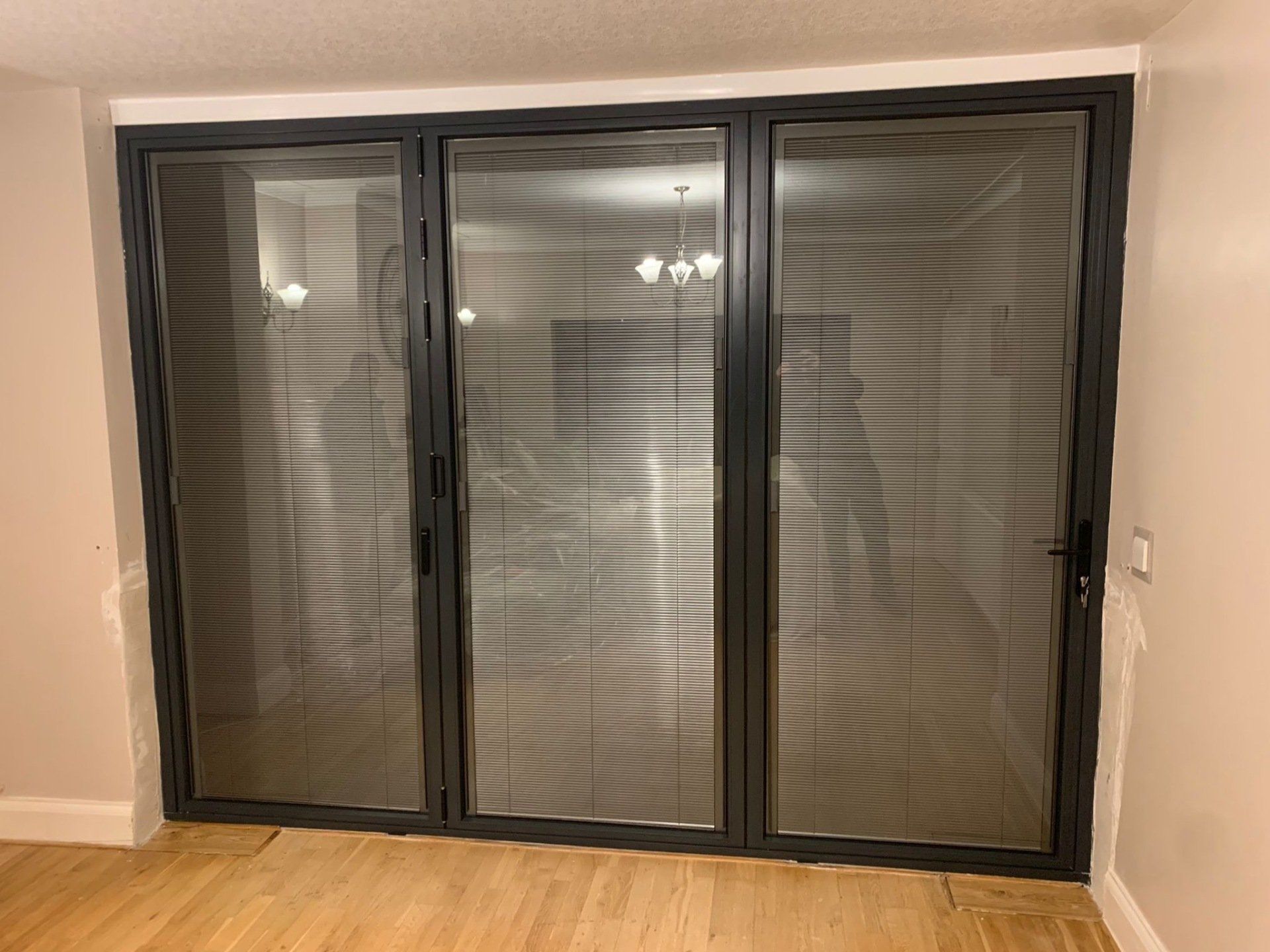 A room with a sliding glass door and blinds on the windows.