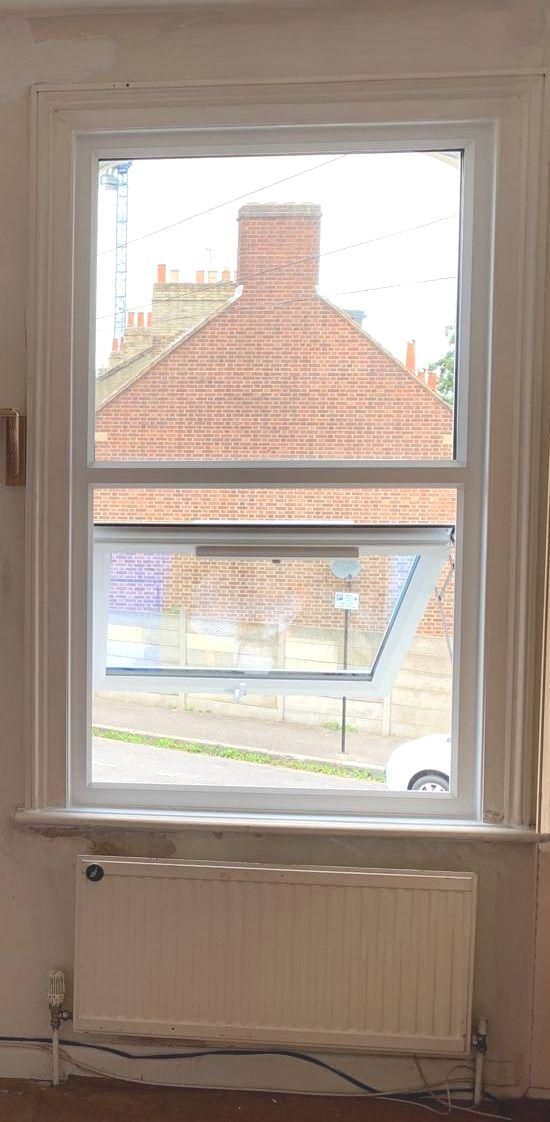 A window with a view of a brick building and a radiator in a room.