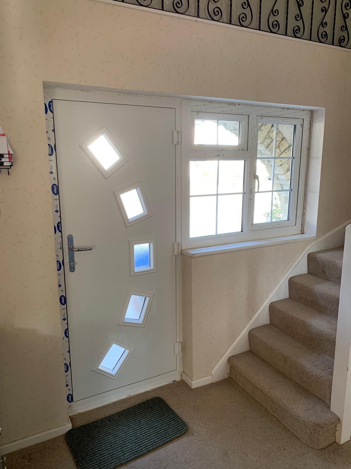 A white door with a window and stairs in a hallway.