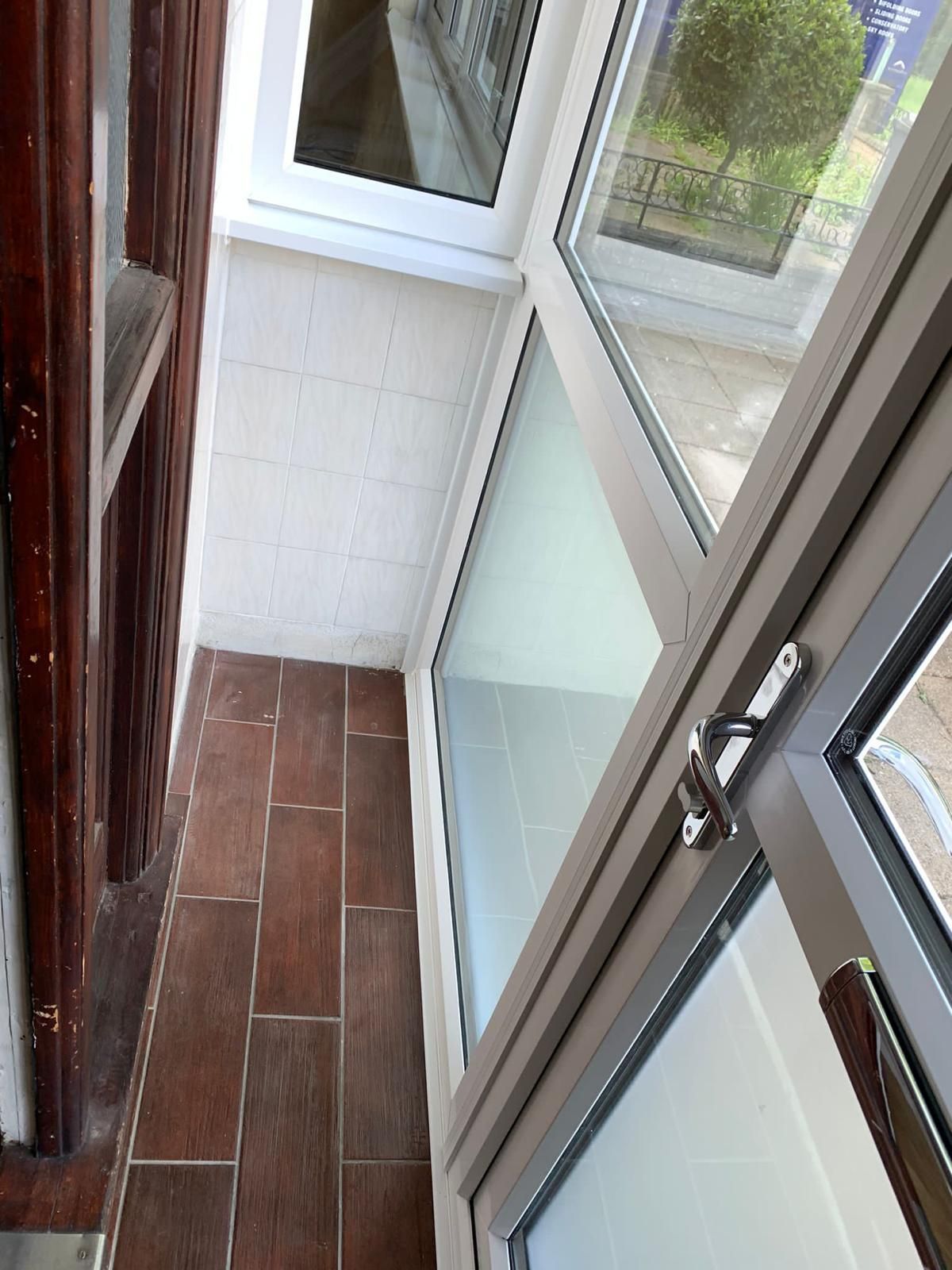 A balcony with a lot of windows and a tiled floor