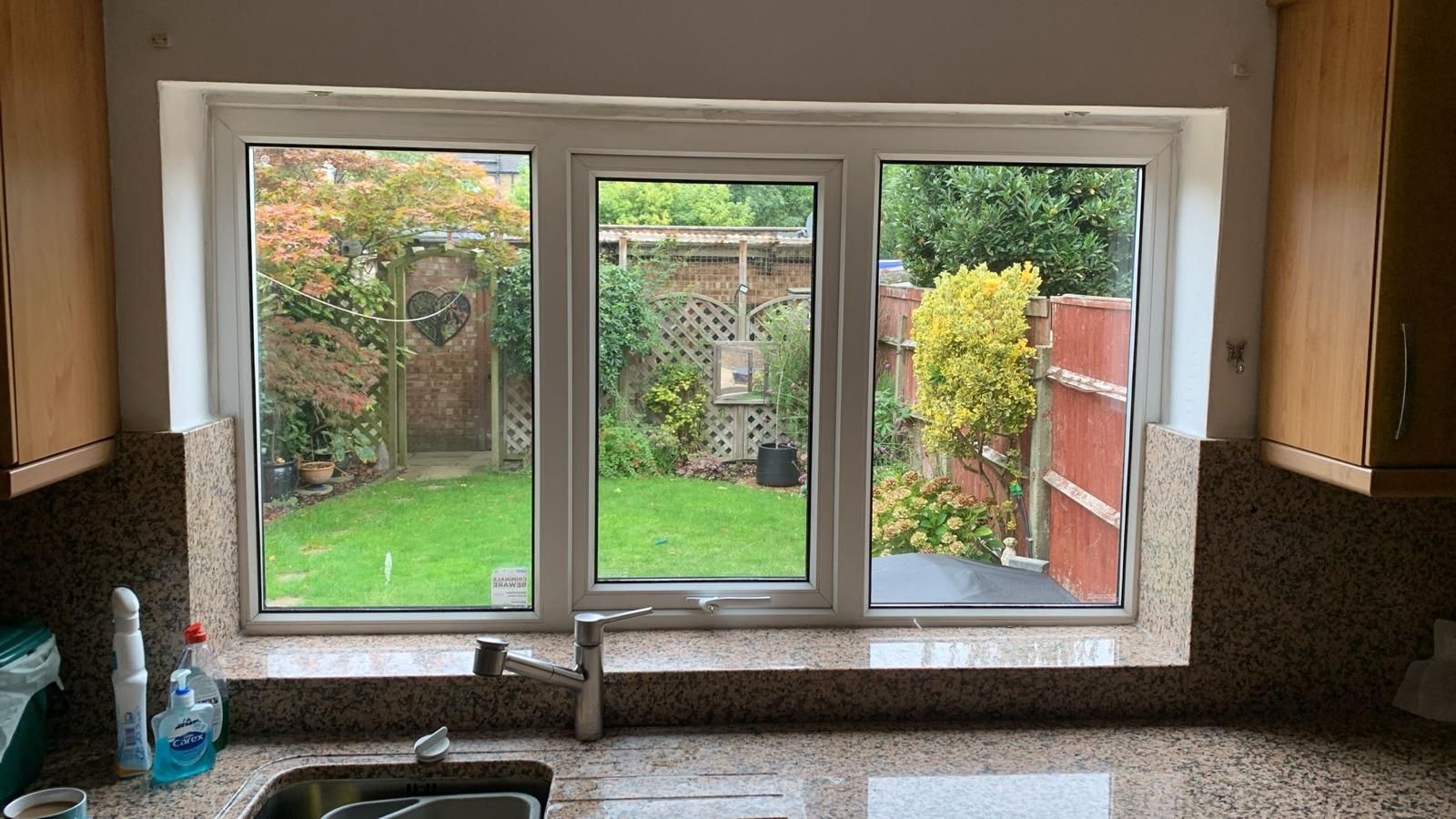 A kitchen with a sink and a window with a view of a garden.