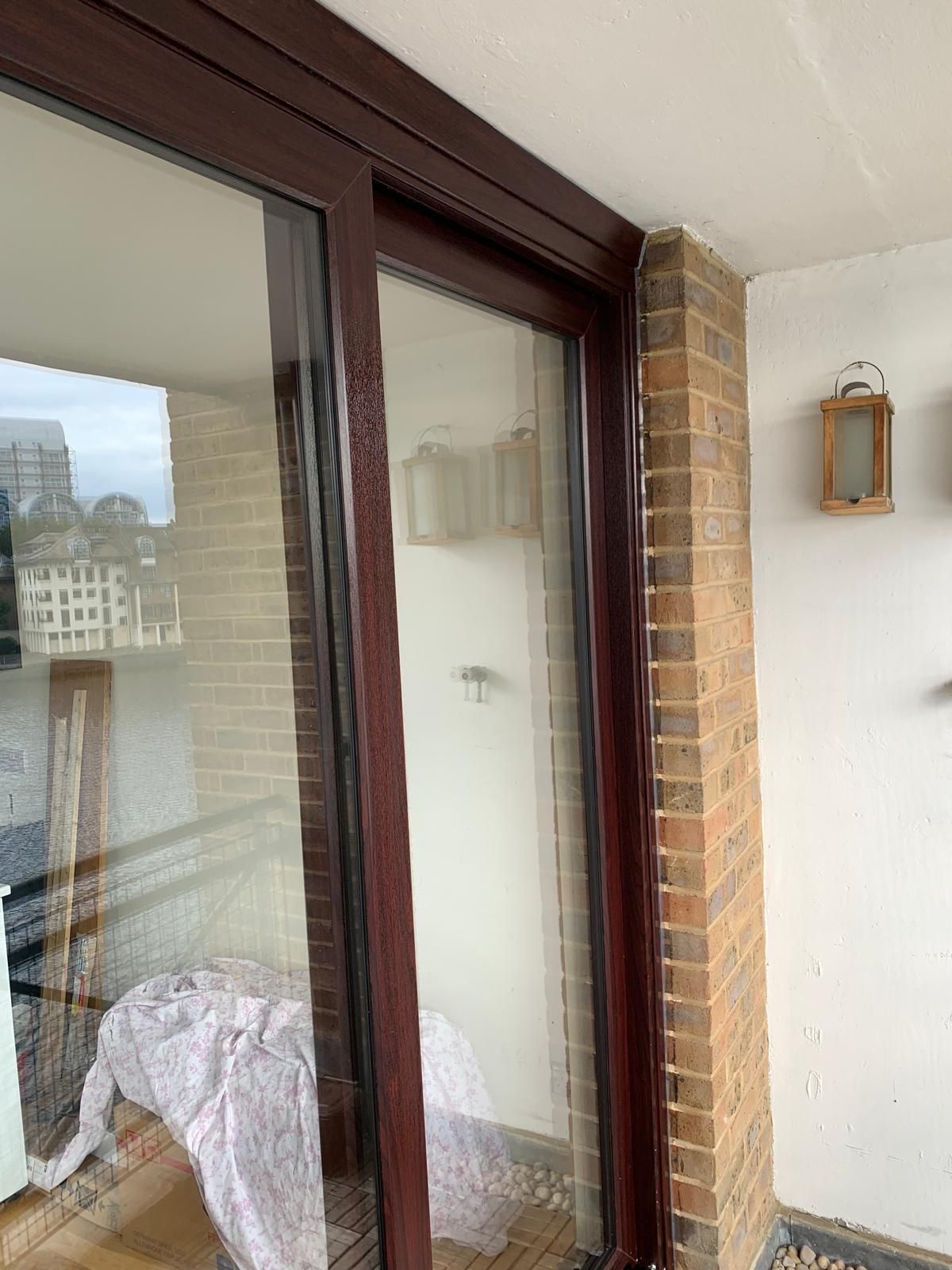 A balcony with a sliding glass door and a brick wall.