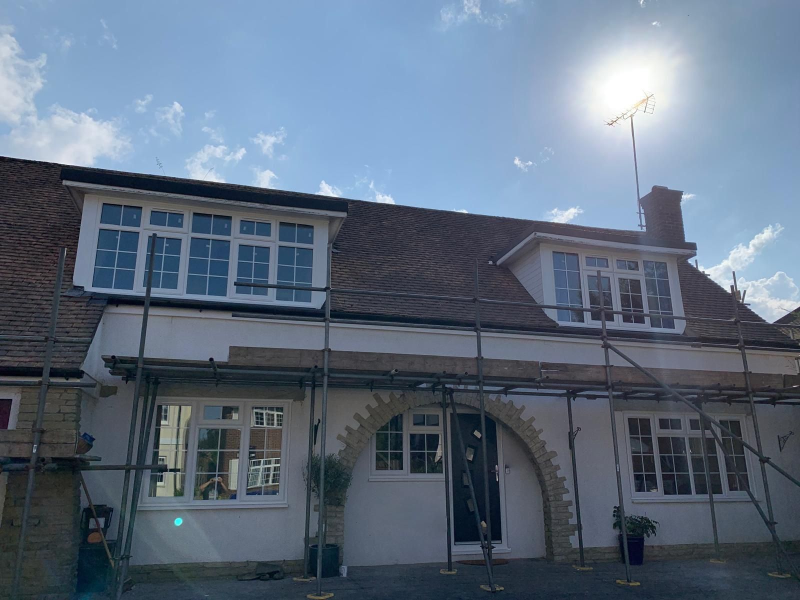 A house with scaffolding around it and the sun shining through the windows.