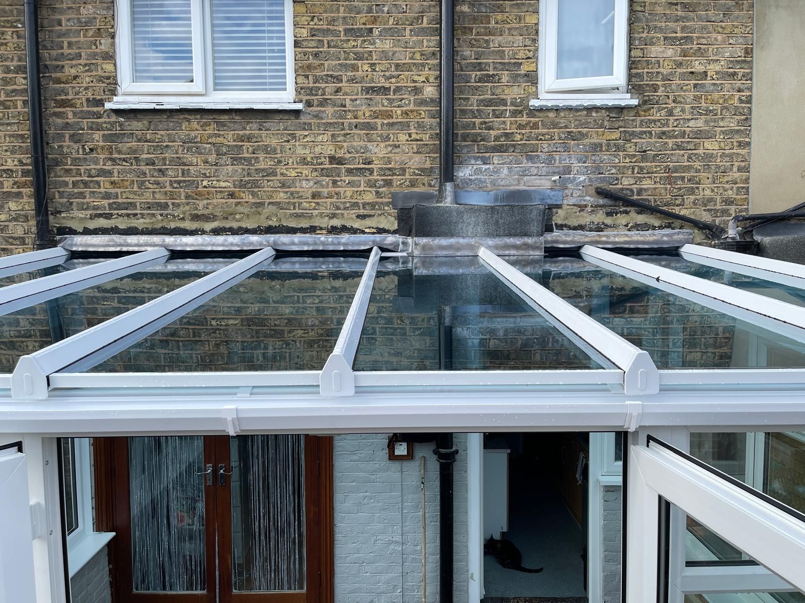 A brick house with a glass roof and a white railing