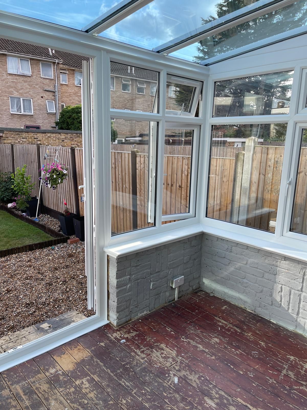 A conservatory with a glass roof and a wooden floor.