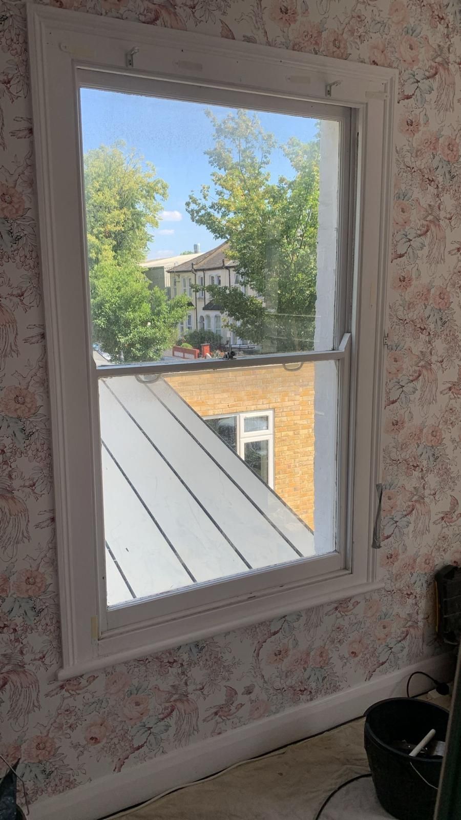 A window in a room with a view of a roof and trees.