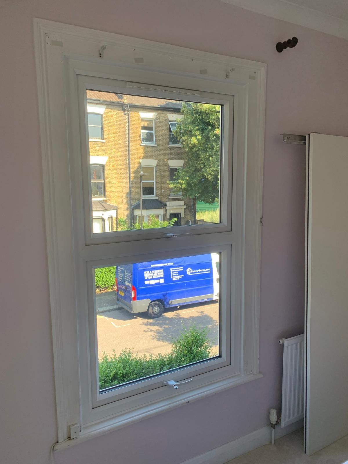 A blue van is parked in front of a window in a room.
