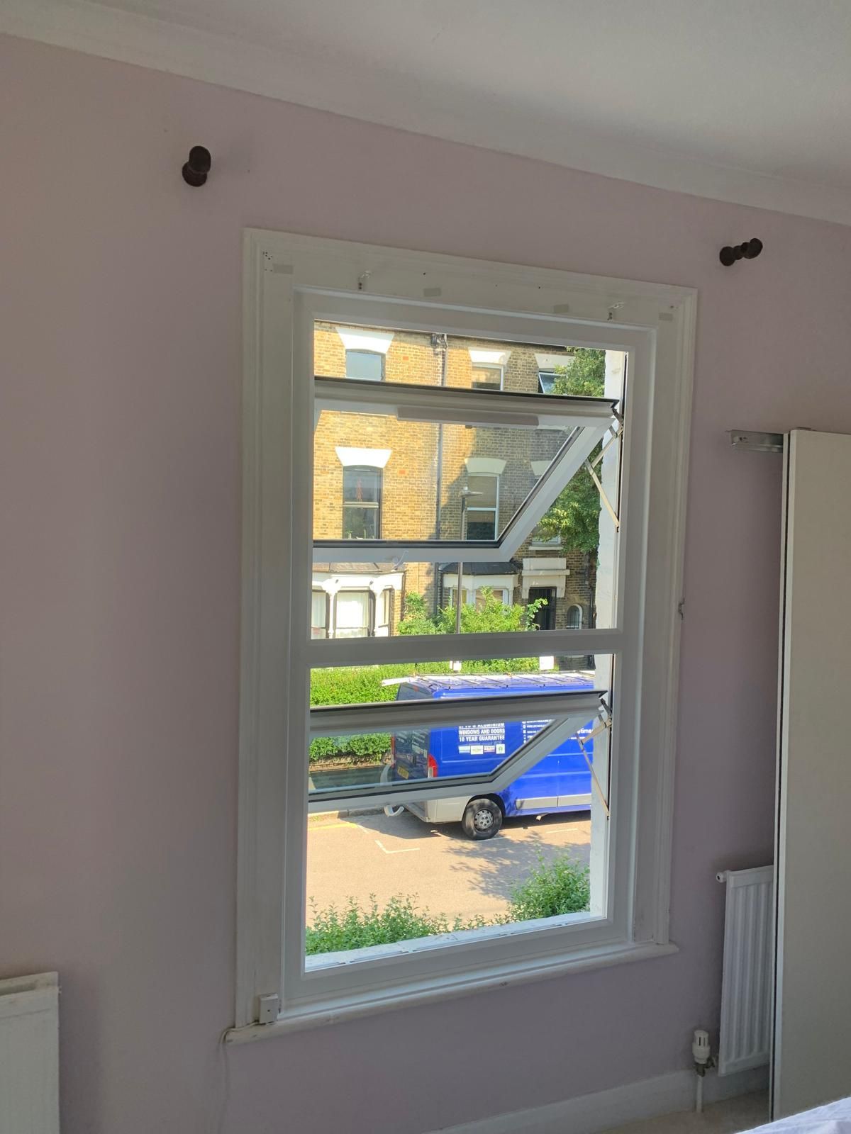 A bedroom with a window and a blue van in the background.