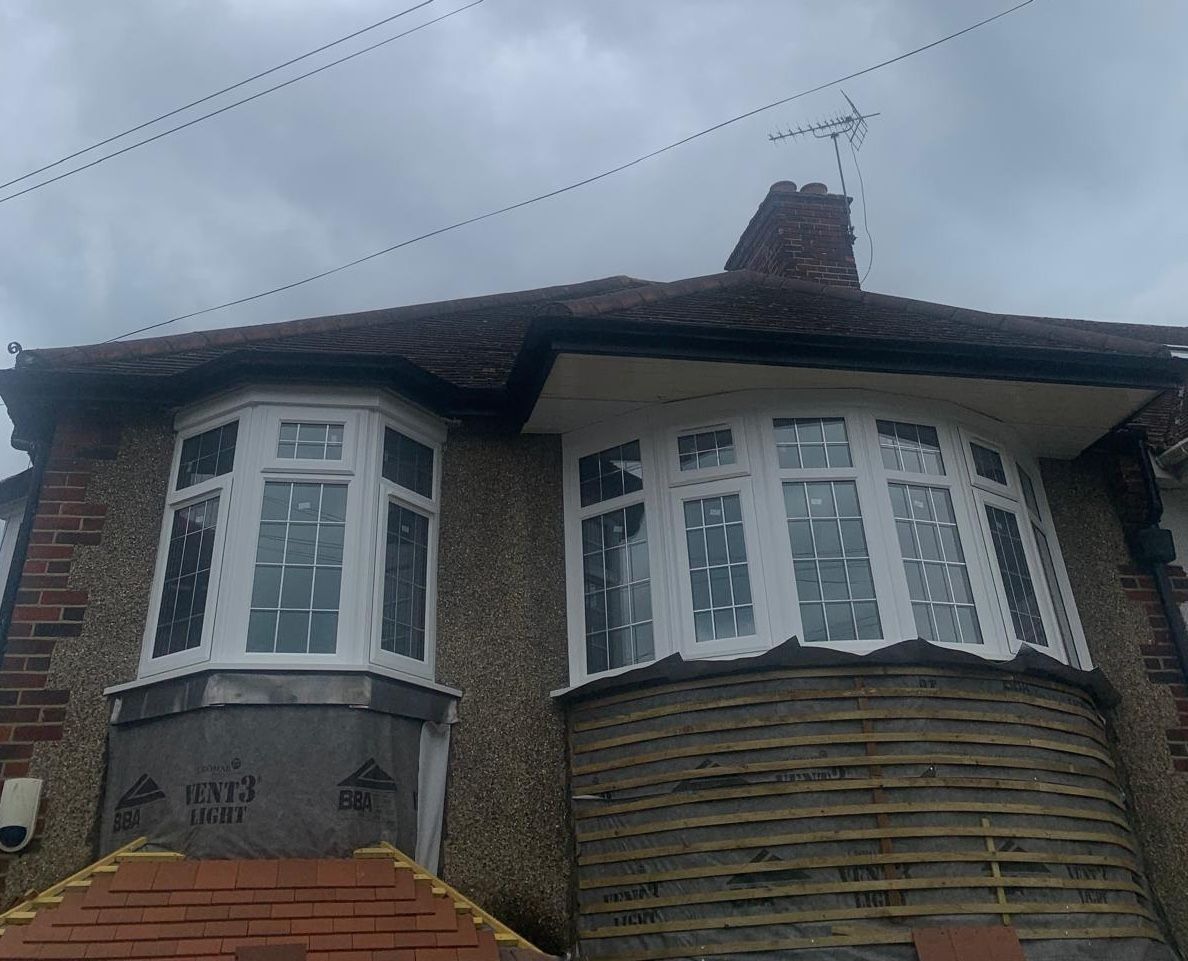 A house with two bay windows and a chimney on the roof.
