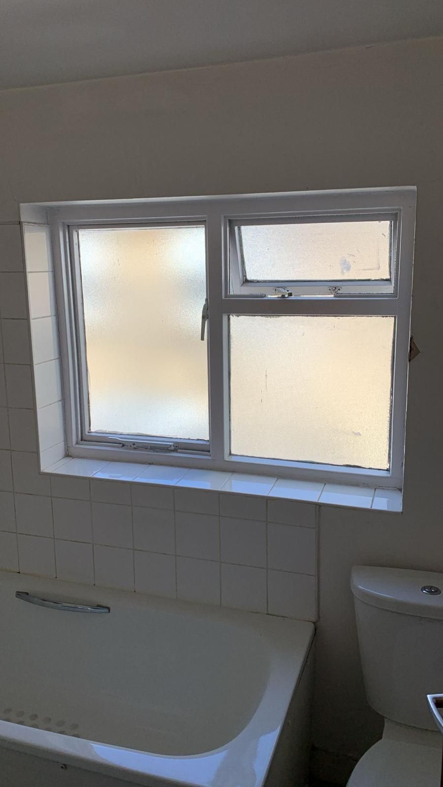 A bathroom with a bathtub , toilet and window.