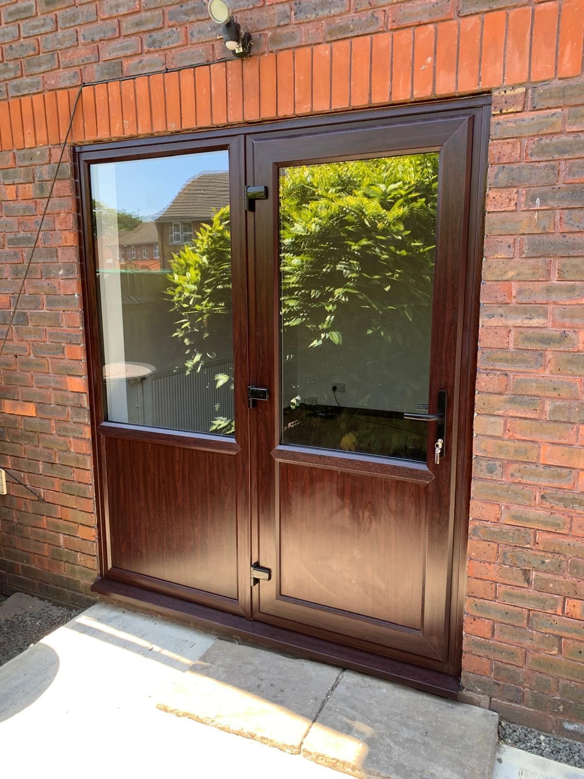 A brown door is sitting on the side of a brick building.