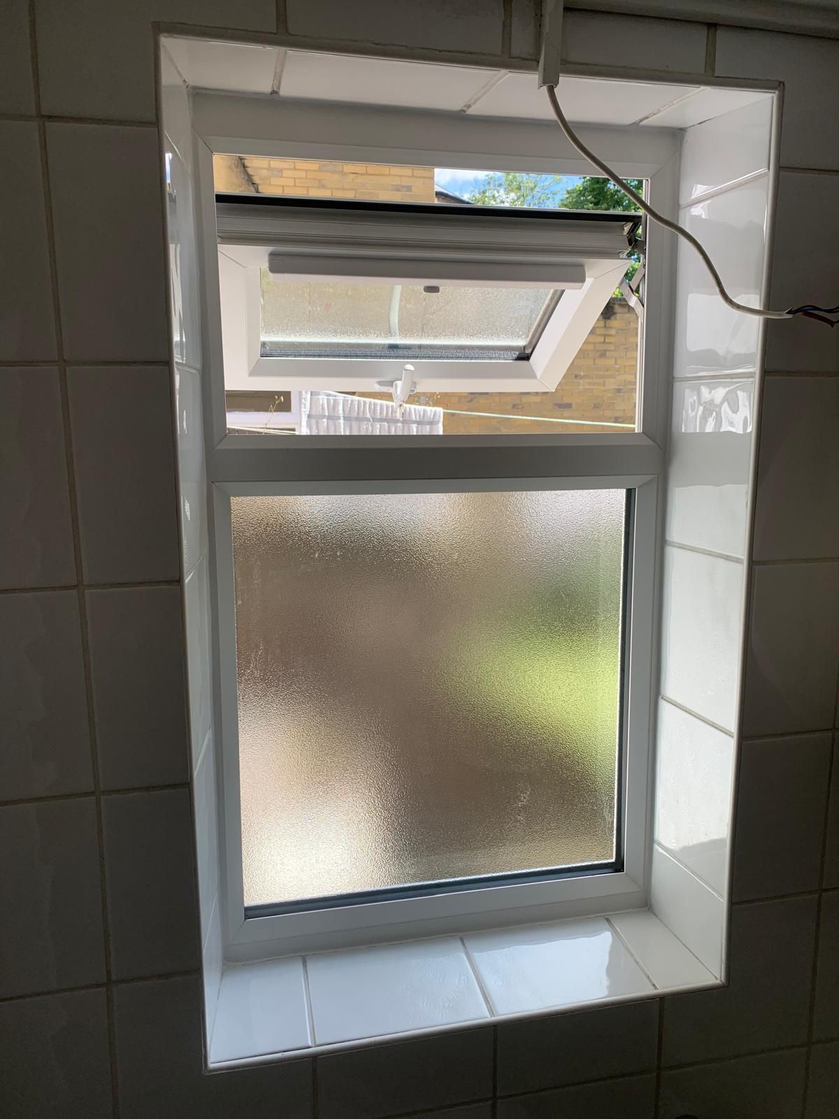 A bathroom window with a white frame and frosted glass.