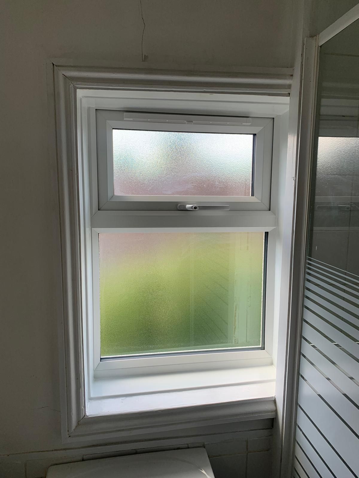 A bathroom with a window and a toilet.