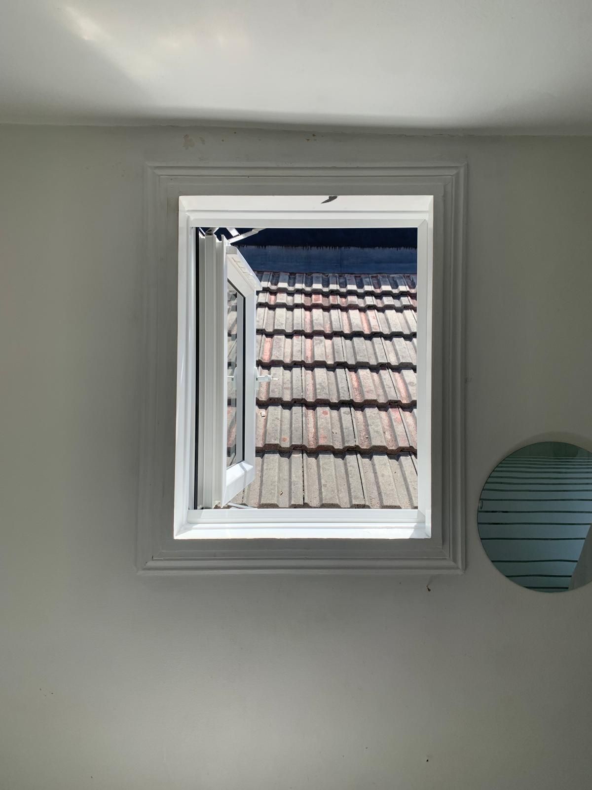 A window with a view of a tiled roof in a room.