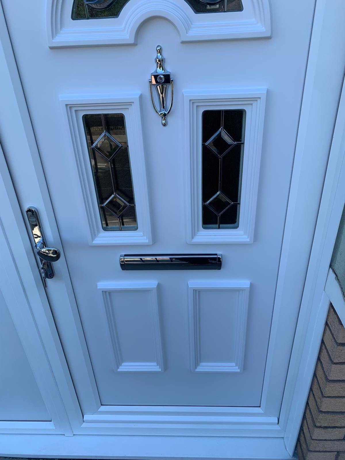 A white front door with stained glass windows and a mailbox.
