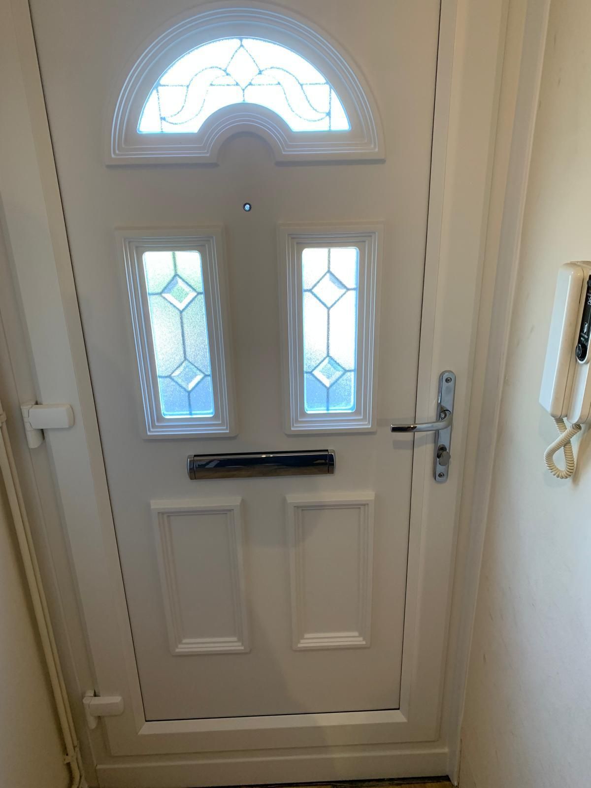 A white door with a stained glass window is in a hallway.