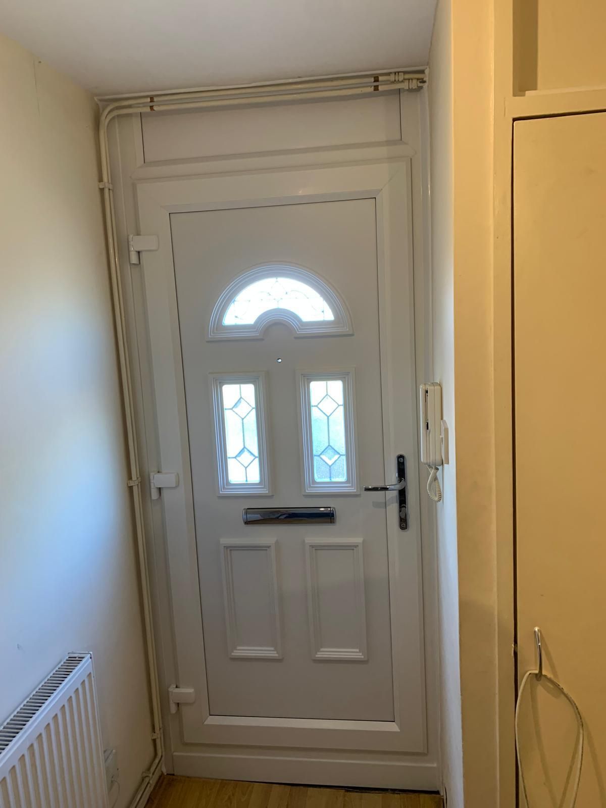 A white door is in a hallway next to a radiator.