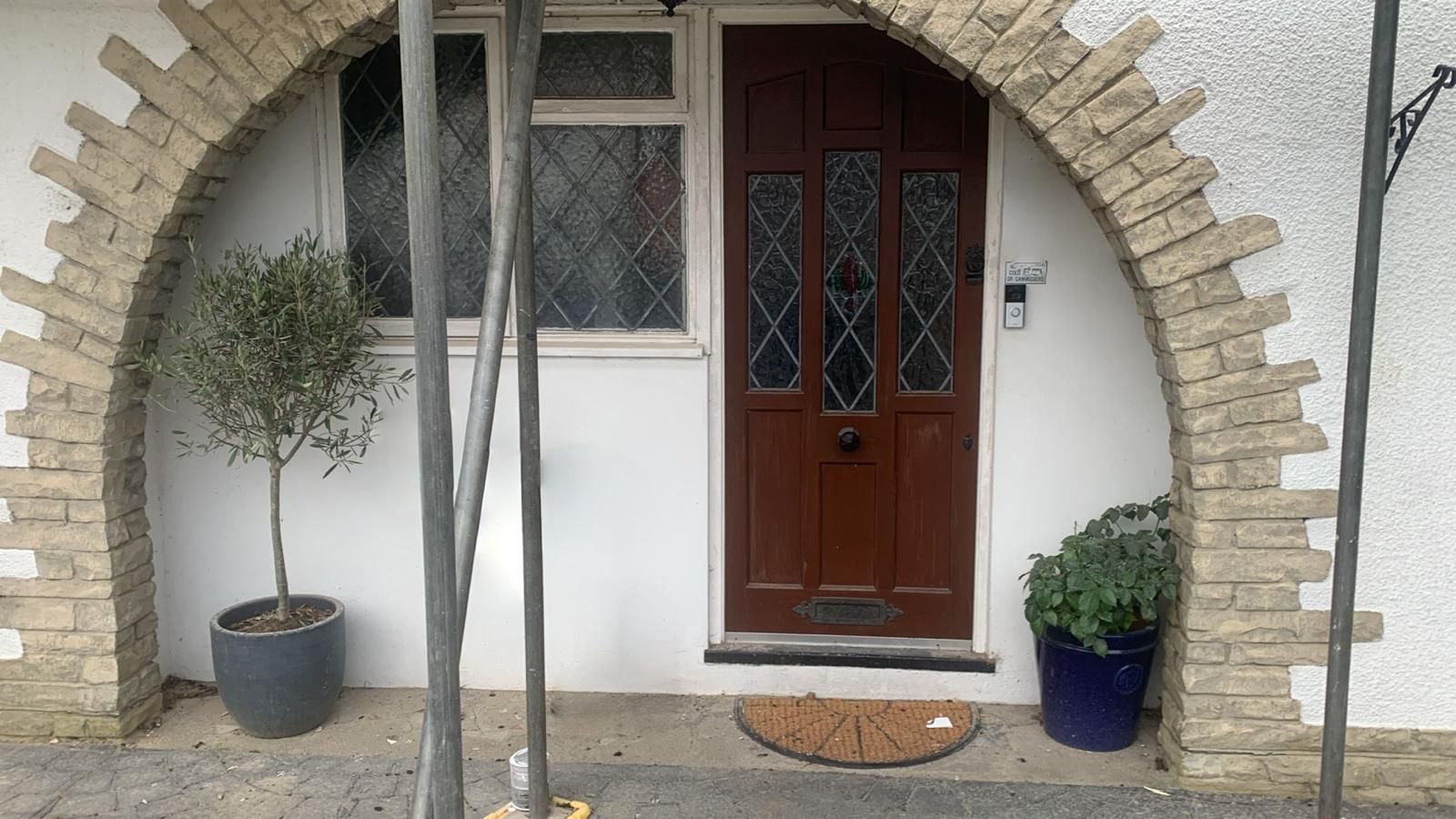 The front door of a house with a brick arch and a brown door.