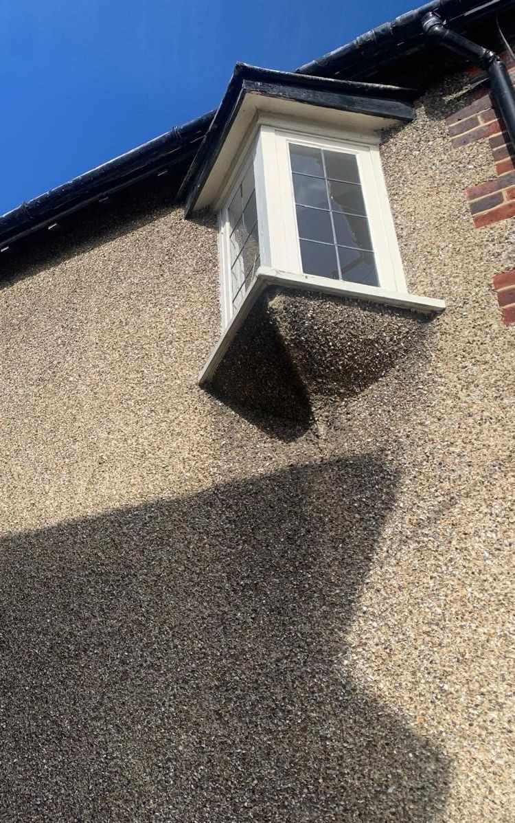 A window on the side of a building with a shadow on the wall.