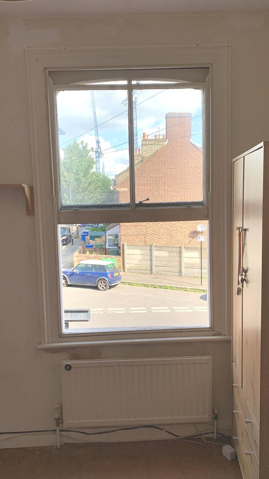 A room with a window and a radiator and a view of a street.