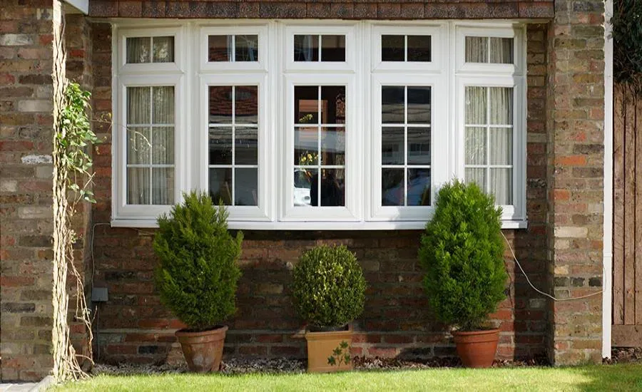 A house with a large window and potted plants in front of it