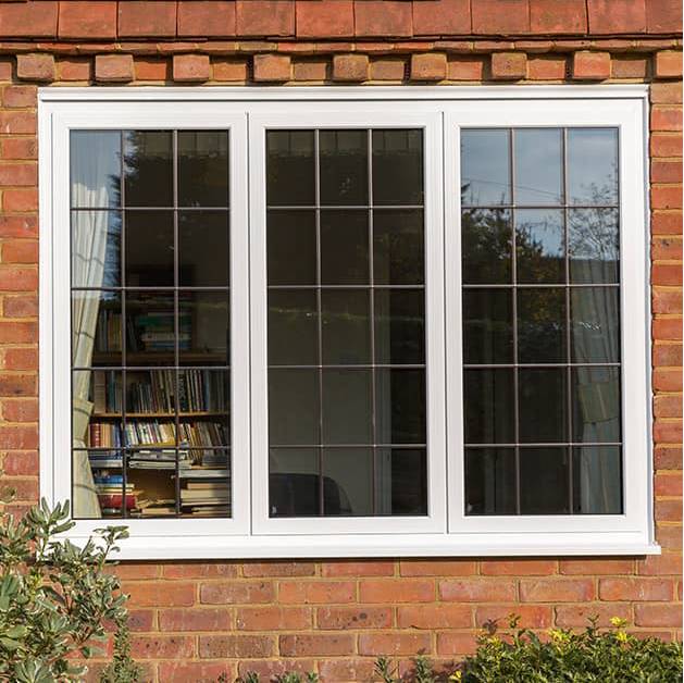 A white window on a brick wall with a bookshelf in the background.