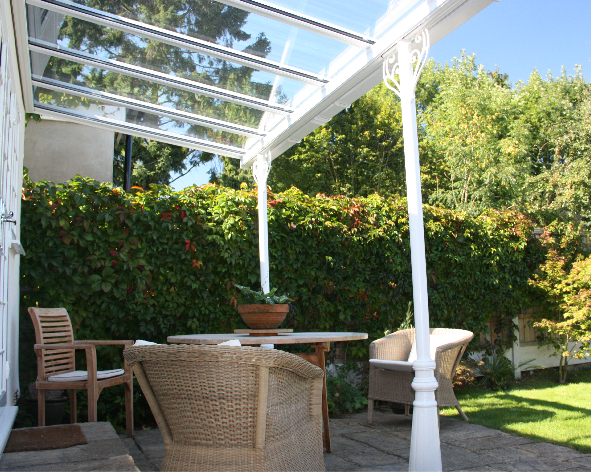 A patio with a table and chairs under a glass roof