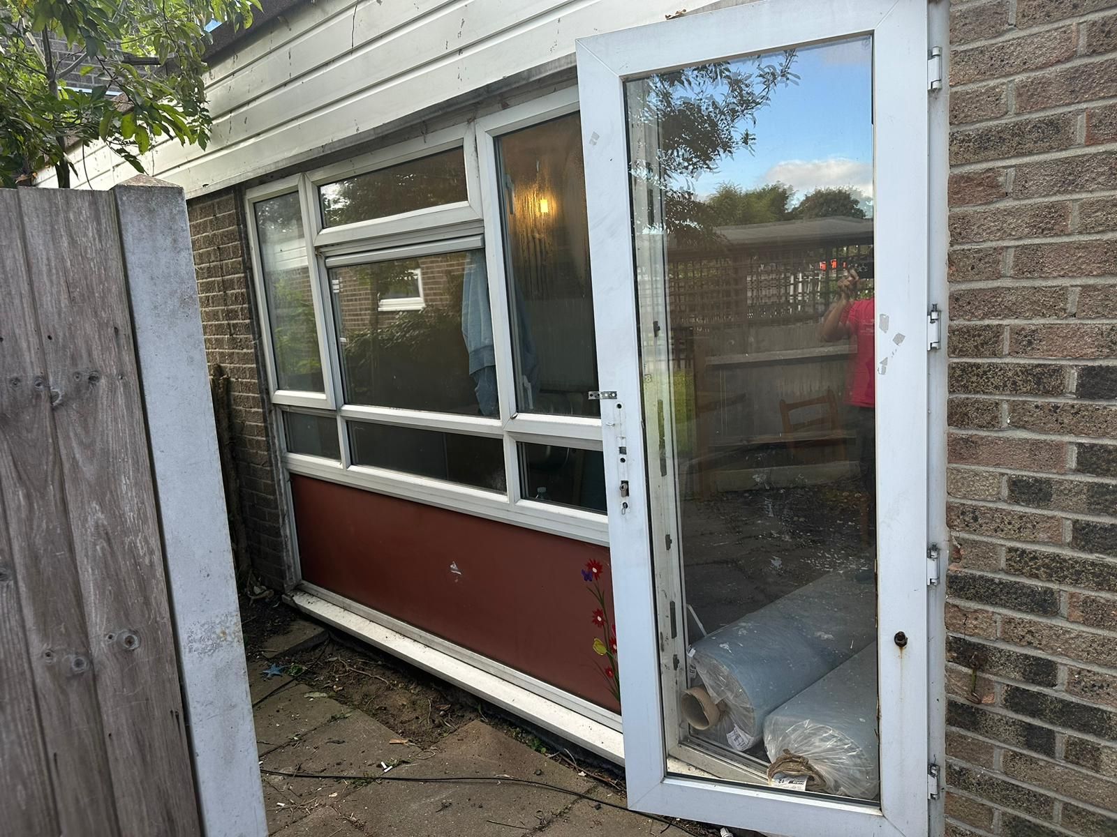 A white sliding glass door is sitting on the side of a brick building.