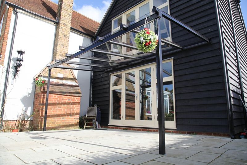 A black house with a canopy and a chair in front of it.