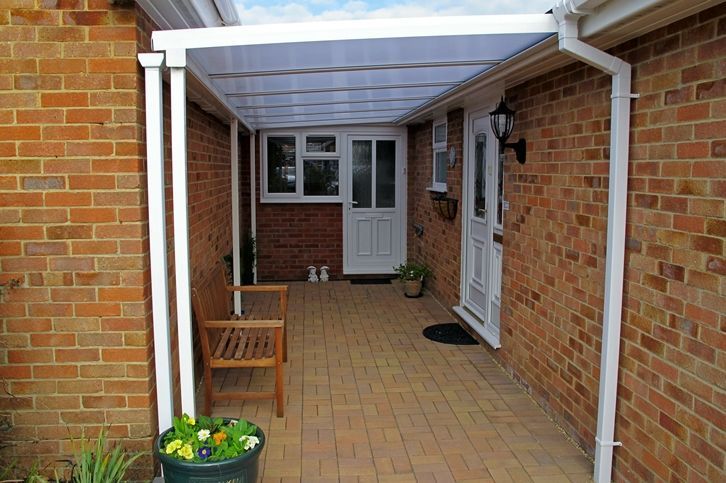 A porch with a bench and a potted plant in front of a brick house.
