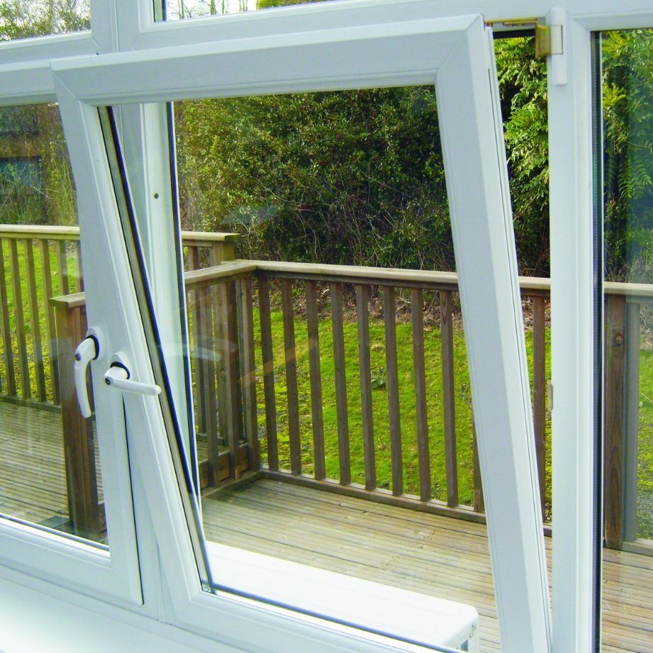 A white window with a view of a deck and trees