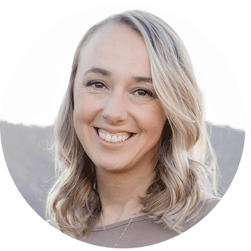 Woman with blonde hair smiling at the camera with mountains in the background