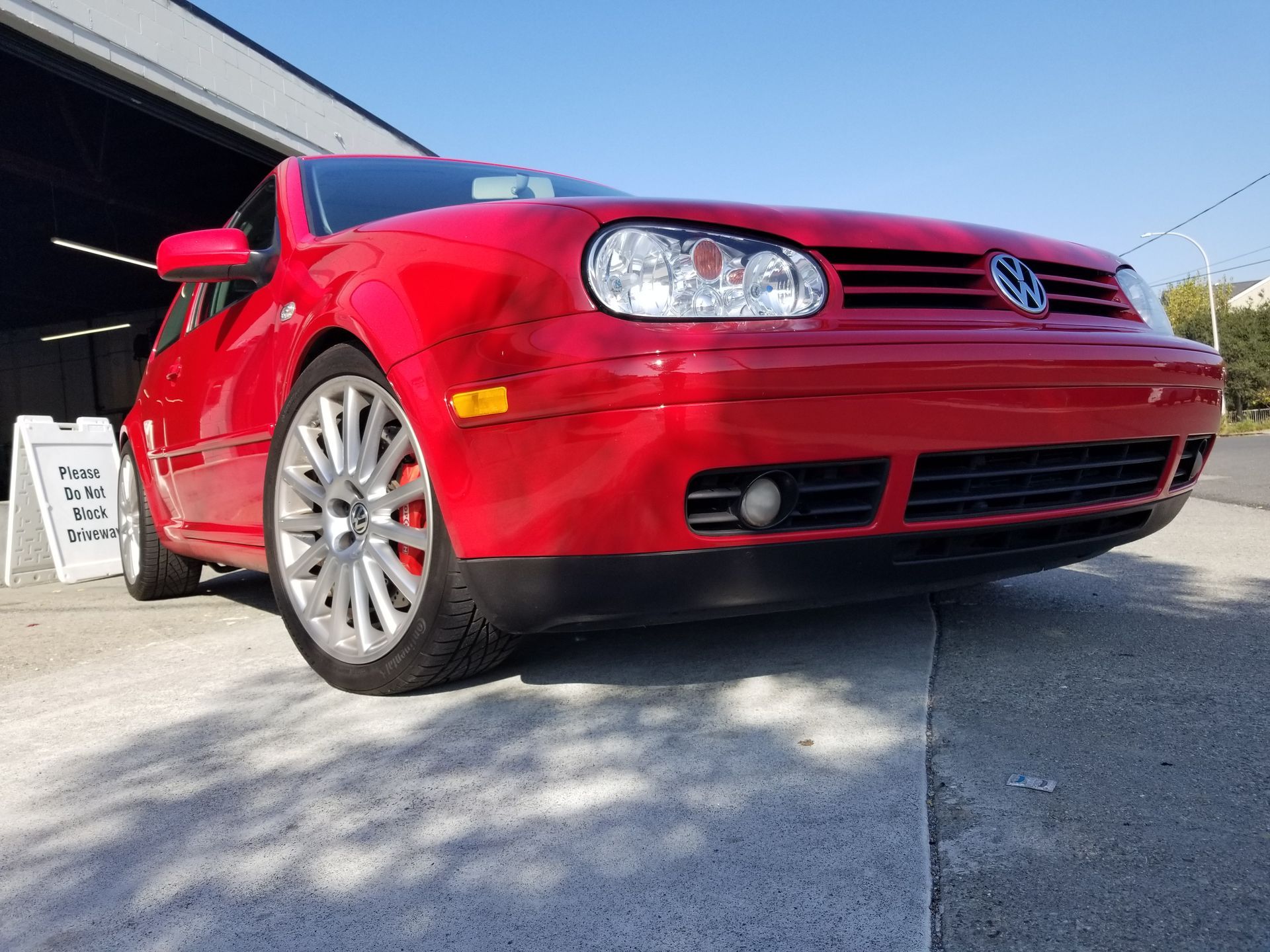 A red volkswagen golf is parked in front of a garage | Griffin Motorwerke