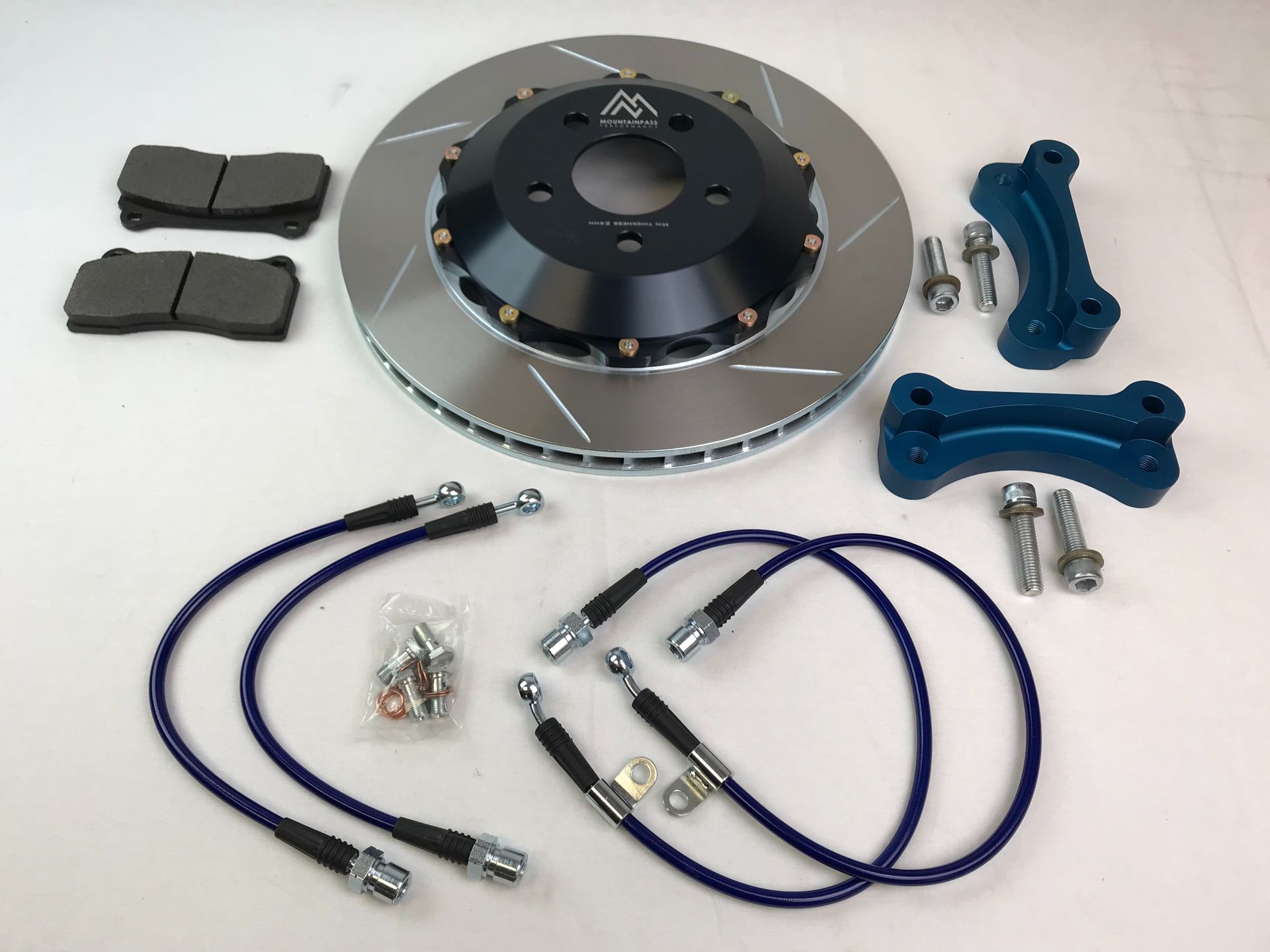 A brake disc with pads and hoses on a white surface | Griffin Motorwerke