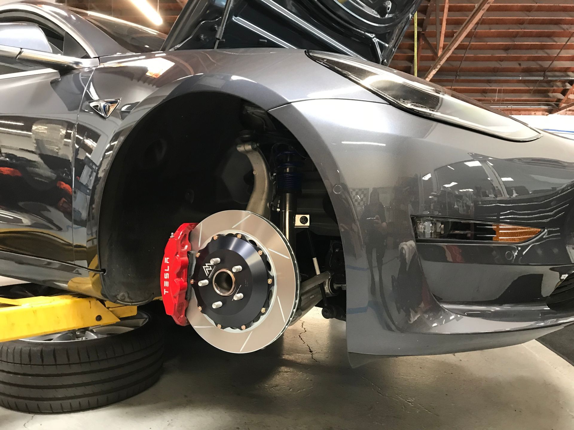 A tesla model 3 is sitting on a lift with the brake pads removed | Griffin Motorwerke