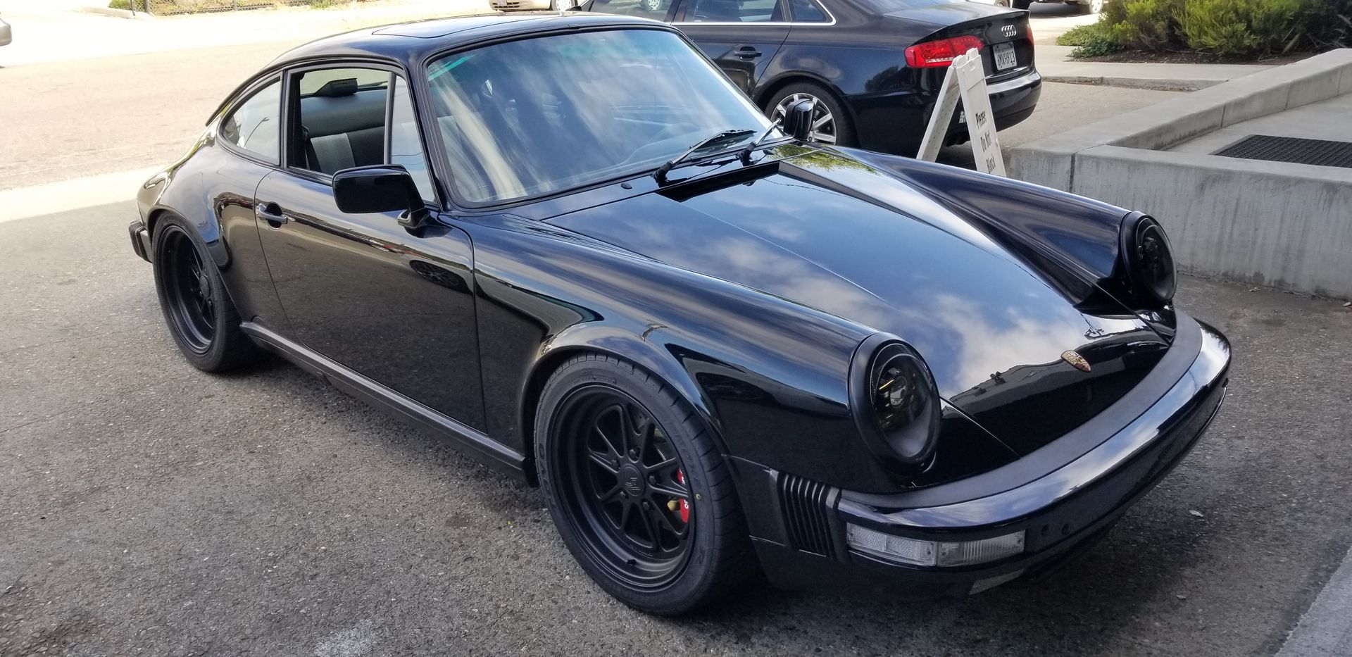 A black porsche 911 is parked in a parking lot | Griffin Motorwerke