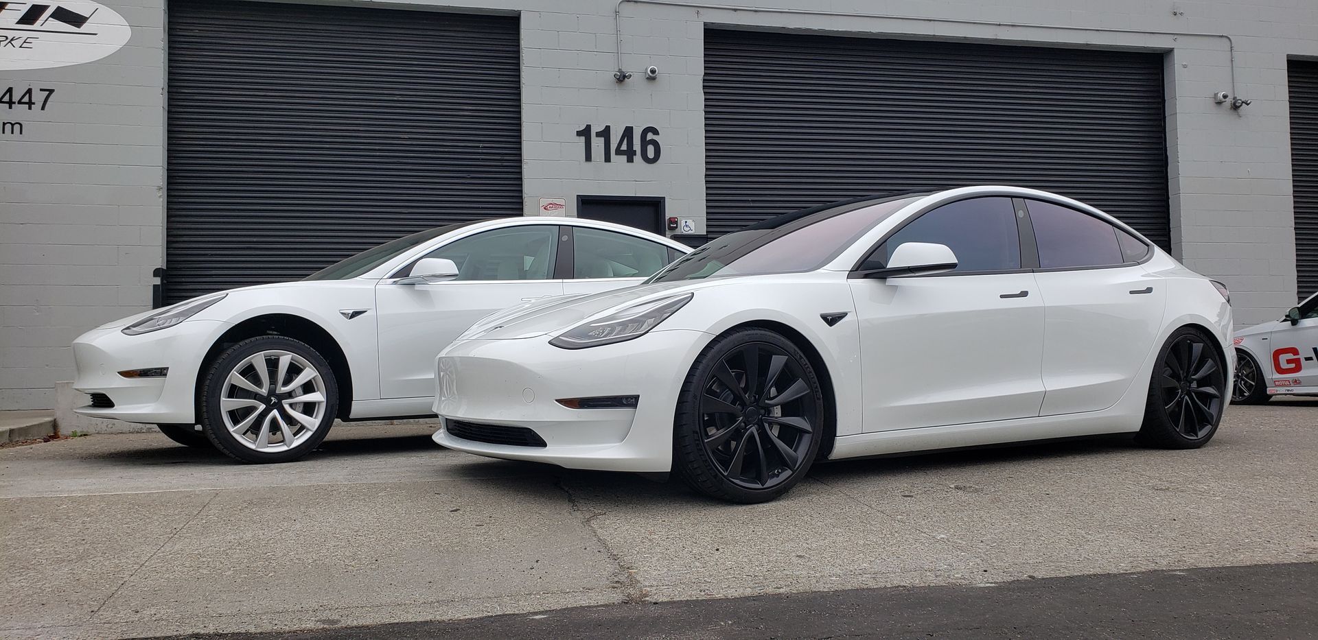 Two white tesla model 3 cars are parked next to each other in front of a garage | Griffin Motorwerke