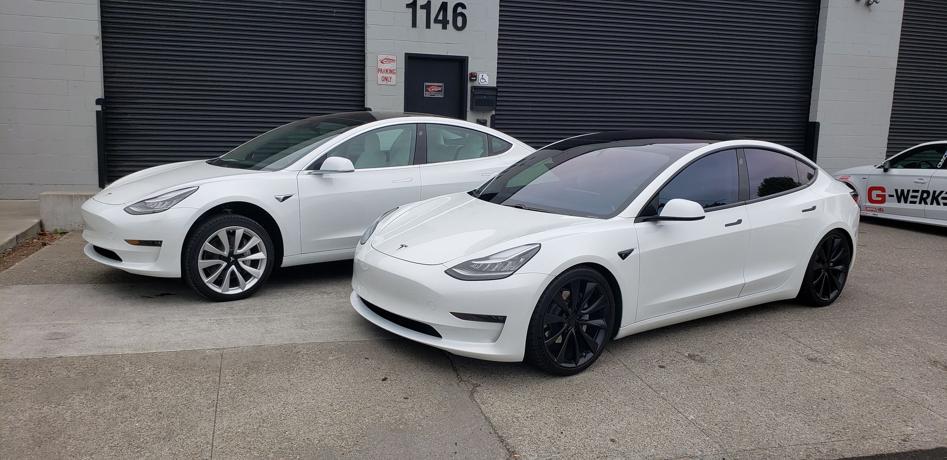 Two white tesla model 3 cars are parked next to each other in front of a building | Griffin Motorwerke