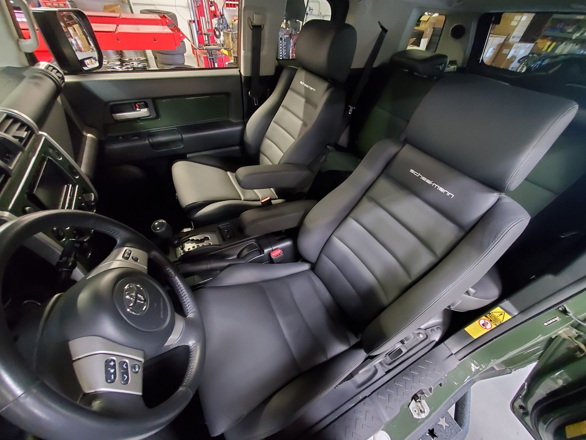The interior of a car with black seats and a steering wheelv