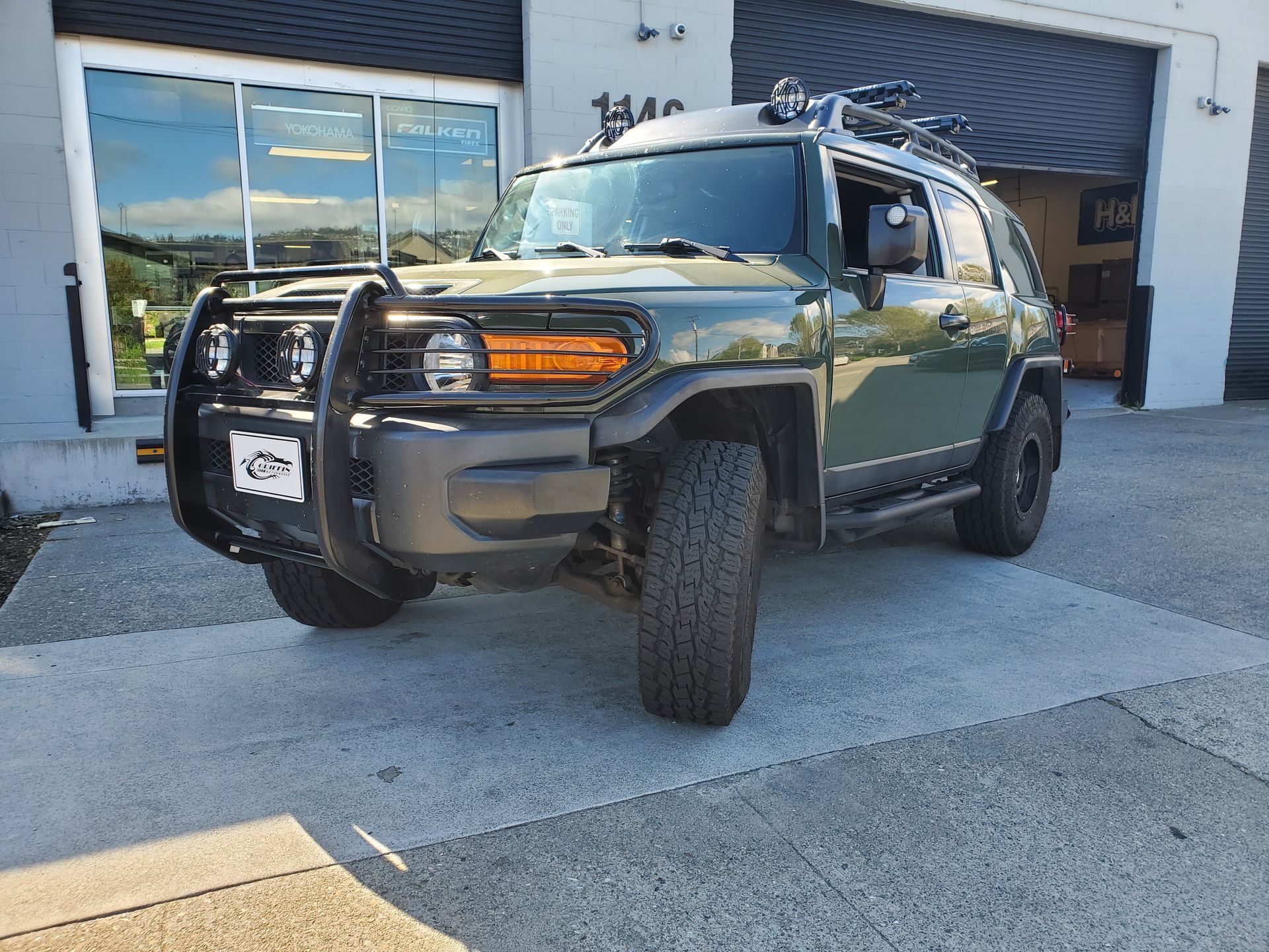 A green toyota fj cruiser is parked in front of a garage | Griffin Motorwerke