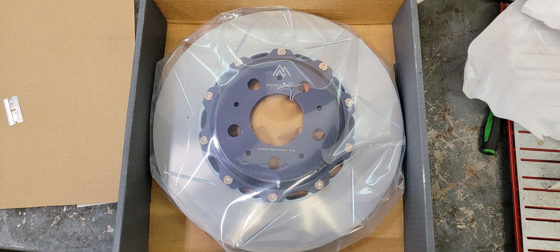 A brake disc is wrapped in plastic and sitting in a box | Griffin Motorwerke