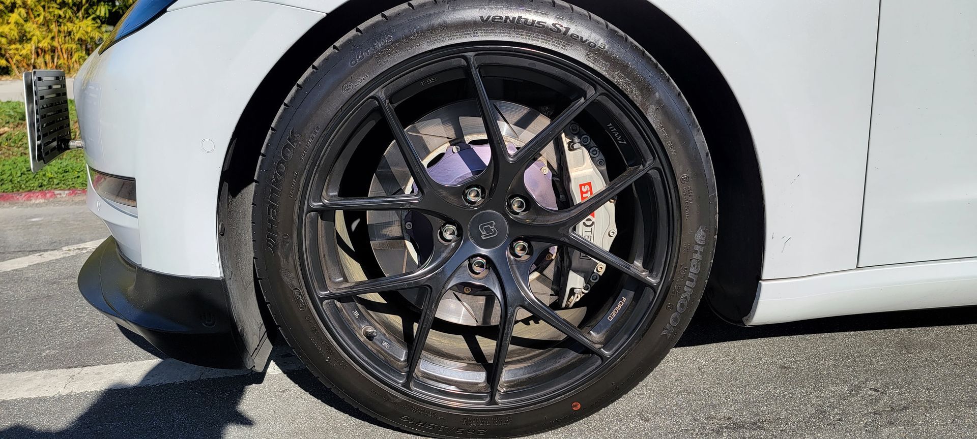 A white car with black wheels and tires is parked on the side of the road | Griffin Motorwerke