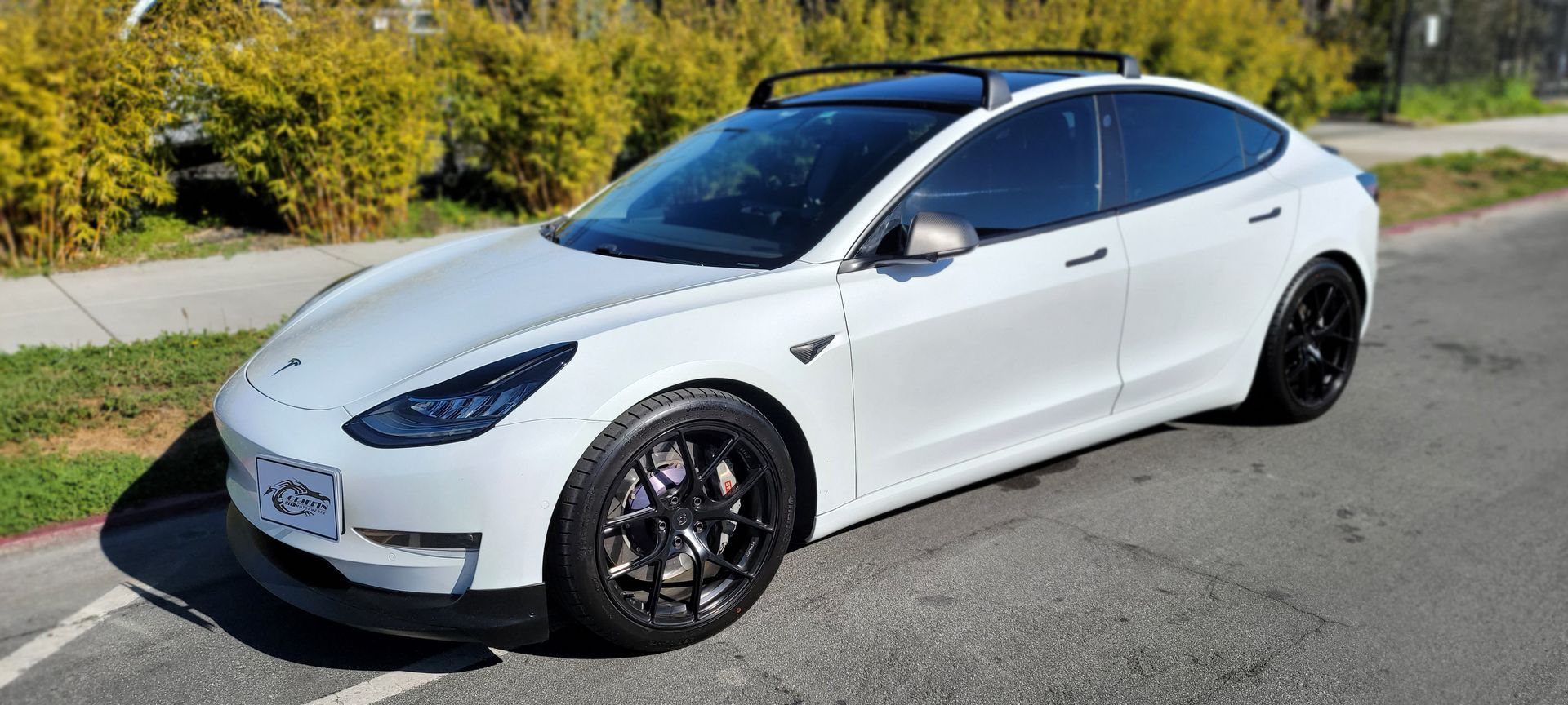 A white tesla model 3 is parked on the side of the road | Griffin Motorwerke